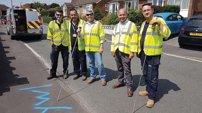 Experienced leakage inspectors stand by the located area marked for repair. Eddy Segal of Utilis (center left) and Nick Haskins of SUEZ Advanced Solutions (center right).