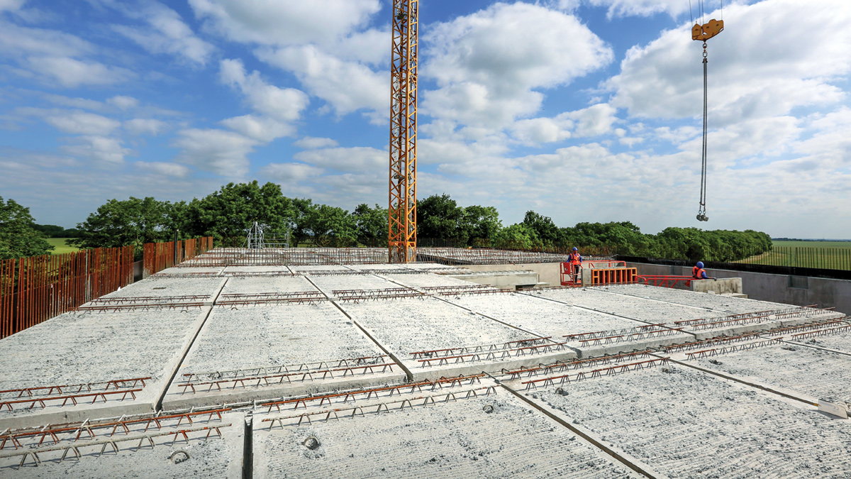 Construction workers guiding precast concrete roof slabs into place - Courtesy of Stonbury
